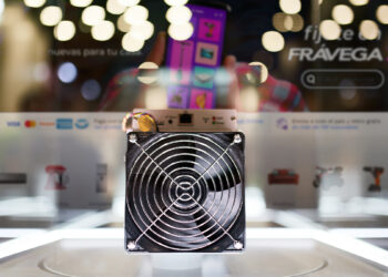 minero ASIC para la minería de bitcoin en exposición con inerfaz de Fravega en el fondo