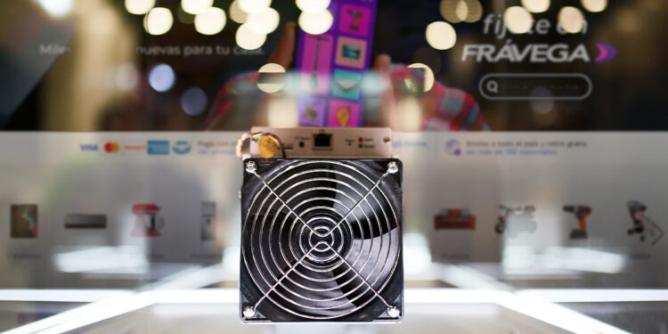 minero ASIC para la minería de bitcoin en exposición con inerfaz de Fravega en el fondo
