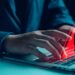 un hombre escribiendo en una computadora portátil y una señal de advertencia roja