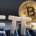 Las siglas ETF sobre un teclado y con una moneda de Bitcoin al fondo