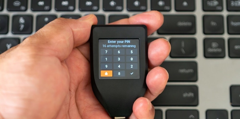 Un dispositivo hardware wallet en una mano de hombre.