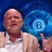 Mike Novogratz con fondo azul con logo de bitcoin detrás, en medio de un globo terráqueo.