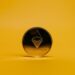 Una moneda dorada con el símbolo de Ethereum en un fondo amarillo