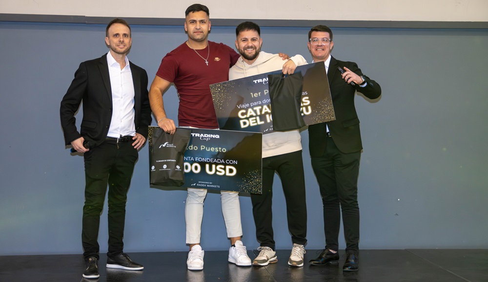 4 hombres jóvenes en el podio, dos de ellos sosteniendo el premio de primer y segundo ganador del torneo de trading de Radex Markets.