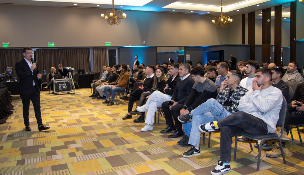 Un hombre en traje habla ante un grupo de traders sentados en la Competencia de traders de Radex Markets.