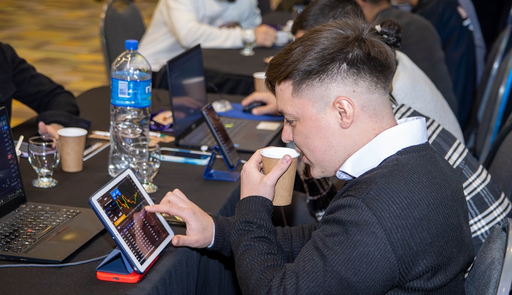 Trader operando en el mercado de criptomonedas sobra una Tablet, mientras toma café.
