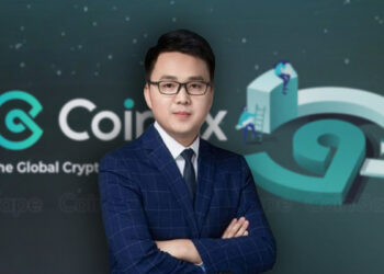 Haipo Yang, CEO de CoinEx, de traje y corbata azul frente al logo de CoinEx.