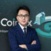 Haipo Yang, CEO de CoinEx, de traje y corbata azul frente al logo de CoinEx.