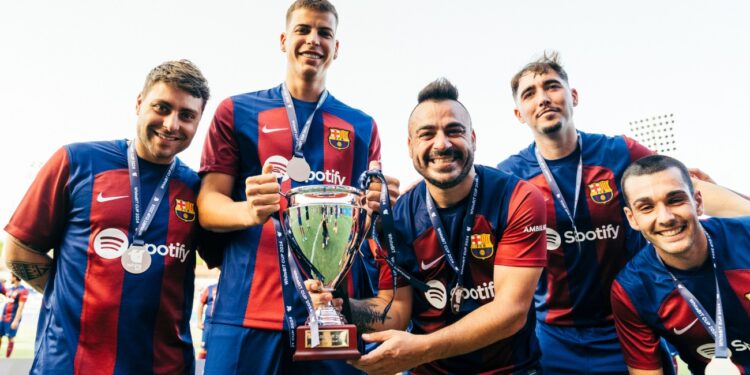Cuatro jugadores del FC Barcelona reunidos sosteniendo un trofeo.