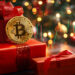 Cajas de regalo debajo de un arbolito navideño con una moneda de bitcoin encima.
