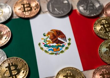 Bandera de México rodeada de monedas físicas con el logo de bitcoin.