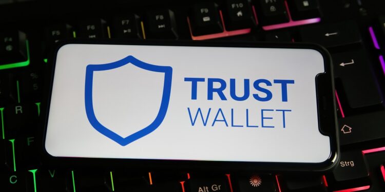 Un celular que muestra "Trust Wallet" en la pantalla apoyado sobre un teclado.