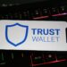 Un celular que muestra "Trust Wallet" en la pantalla apoyado sobre un teclado.