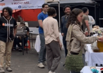 Una persona con una camiseta en la que se lee la palabra bitcoin camina en un mercado bitcoiner en México.