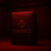 Una wallet de Binance iluminada por una luz roja, como de habitacion de revelacion de fotos .
