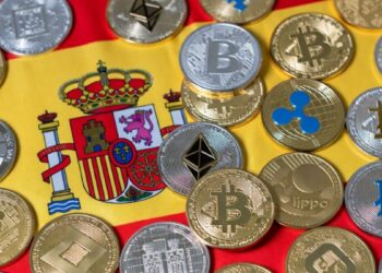 Muchas criptomonedas y detrás la bandera de España