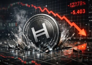 Moneda física de Hedera hundiéndose y rompiendo una superficie con gráficos financieros, mientras un gráfico rojo descendente al fondo.