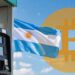 Bandera de Argentina junto a una estación de gasolina y un logo de bitcoin.