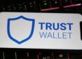 Un celular que muestra "Trust Wallet" en la pantalla apoyado sobre un teclado.