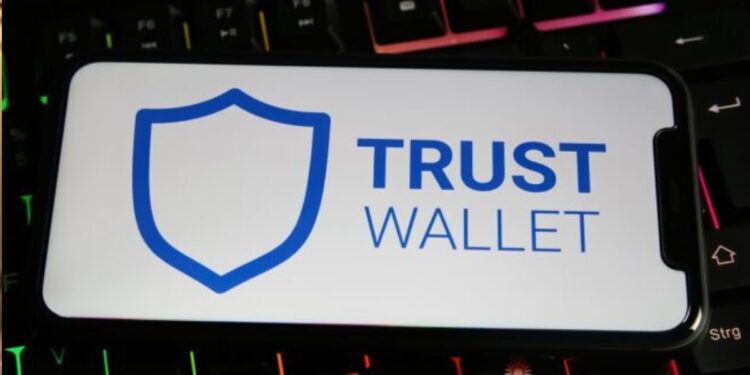 Un celular que muestra "Trust Wallet" en la pantalla apoyado sobre un teclado.